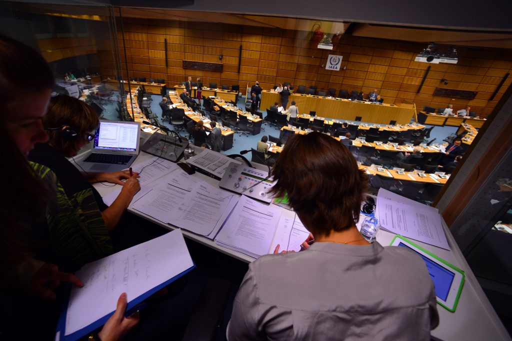 Konferenzdolmetscherinnen bei der Arbeit in der Kabine mit Blick auf ein Plenum bei der IAEA